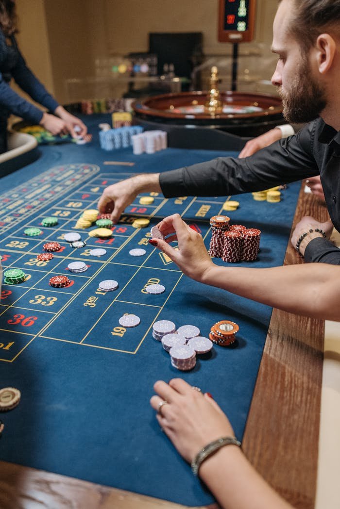 A bearded man engaged in a poker game at a casino table, placing casino chips.